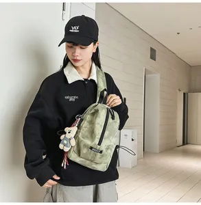 Model wearing a green tie-dye sling bag with a cute bear pendant in a modern hallway