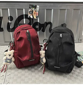 Close-up view of wine red and black casual outdoor chest bags with plush bear charms