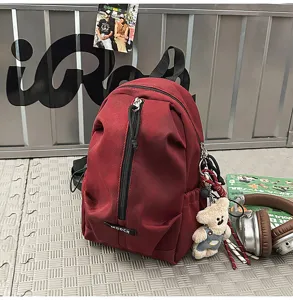 Burgundy mini backpack shown with casual props like headphones and a teddy bear