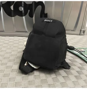 Close-up of a black outdoor chest bag with MGDCH logo on a textured gray background