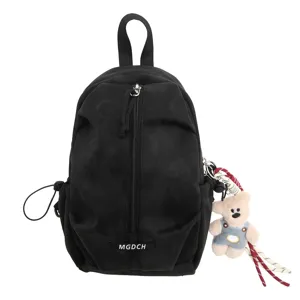 Macro view of a black canvas sling bag featuring a decorative bear plush charm detail