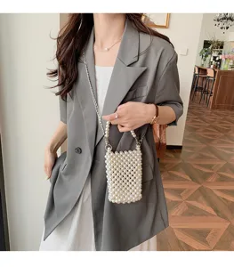 Stylish model showcasing a delicate white woven pearl crossbody phone bag with chain.