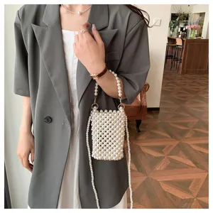 Detailed view of fashionable white faux pearl beaded mini mobile phone bag with strap