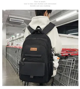 Une personne portant un sac à dos d'école noir minimaliste avec un charme de canard.