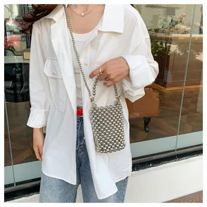 Detail view of a stylish silver beaded crossbody phone bag worn by a model in a white shirt