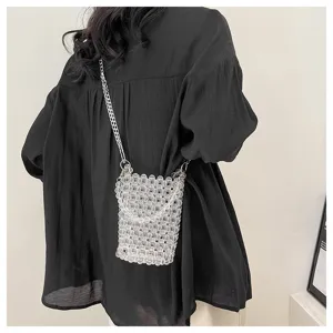 Detail view of a handmade transparent beaded crossbody phone bag worn over a black shirt
