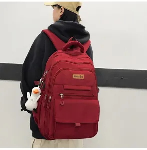 Détail du grand sac à dos d'écolier rouge foncé minimaliste porté par un modèle vue de dos