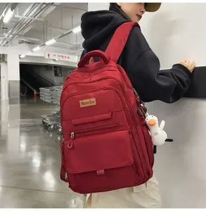 Vue détaillée d'un sac à dos en nylon bordeaux porté par un mannequin en milieu urbain.