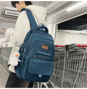 Vue détaillée d'un sac à dos d'étudiant bleu marine épuré avec porte-clé canard