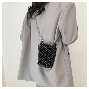 Detail view of a chic black beaded crossbody phone bag worn over a gray oversized blazer.