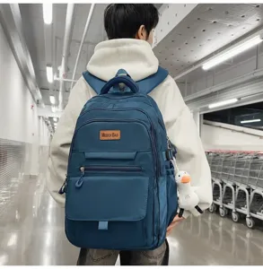 Étudiant portant un grand sac à dos bleu minimaliste de haute capacité dans un couloir.