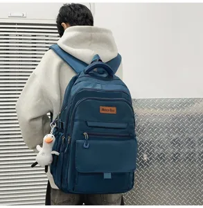 Vue arrière d'un étudiant portant un grand sac à dos bleu avec un joli pendentif canard