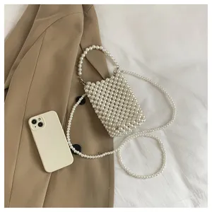 Close-up detail of stylish white beaded pearl crossbody phone bag on beige fabric