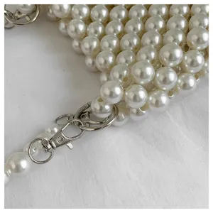 Close-up detail of the metal lobster clasp and elegant pearl weave texture on a shoulder bag.