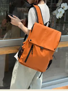 Détail d'un grand sac à dos orange imperméable de style moto porté par un modèle