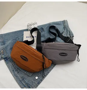 Detail der orangefarbenen und grauen Utility-Brusttaschen mit TENGRUN-Logo auf Denim