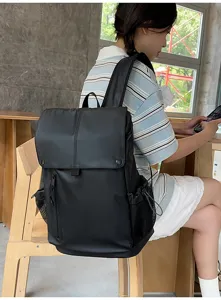 Sac à dos étanche noir de grande capacité porté par un mannequin dans un café