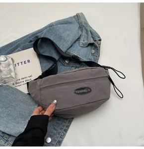 Detailansicht einer grauen Nylon-Gürteltasche mit TENGRUN-Logo auf einer Denim-Hintergrundjacke