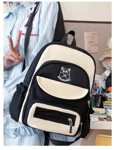 Detail of the black and cream color-blocked schoolbag with cute cat embroidery.