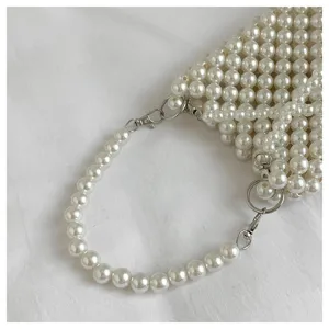 Close-up view of an elegant handcrafted white pearl beaded crossbody bag with a metal clasp
