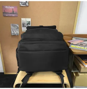 Vue détaillée d'un grand sac à dos noir minimaliste pour étudiant sur une chaise en bois