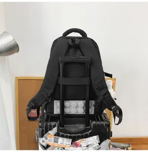 Vue détaillée d'un sac à dos noir minimaliste avec passant trolley sur une valise