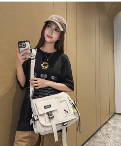 Detail view of a model wearing a beige nylon messenger bag for casual travel and school use