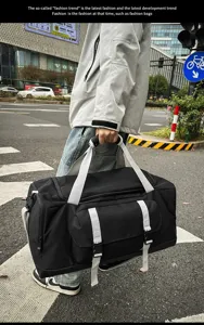 Persona che porta una grande borsa sportiva nera con cinghie bianche in un ambiente urbano.