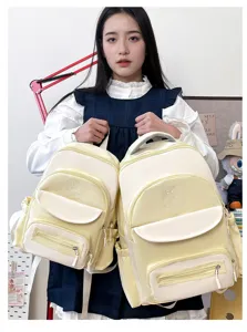 Comparison of two sizes of cute cream-yellow school backpacks held by an Asian model.