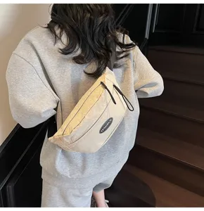 Die Rückansicht einer beigen minimalistischen Brusttasche an einem Modell in Grau