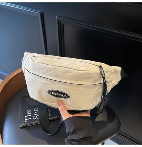 Nahaufnahme-Detail einer uniseks cremefarbenen Brusttasche mit dem Tengrun-Logo-Aufnäher