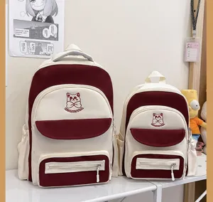 Pair of cream and maroon academy style backpacks with cute cat embroidery details.