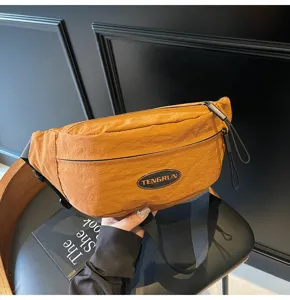 Detailaufnahme einer orangefarbenen Nylon-Brusttasche mit ovalem Aufnäher und Reißverschluss