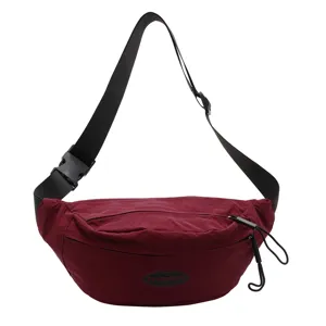 Detailansicht einer weinroten Bauchtasche mit verstellbarem Riemen und Markenlogo-Patch
