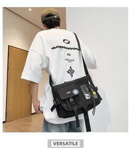 Black nylon messenger bag styled with an oversized white graphic tee on a male model.