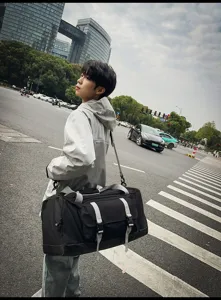 Borsa da viaggio nera moderna con cinturini grigi indossata da un modello maschile