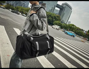 Uomo che trasporta un grande borsone nero e grigio per lo sport e i viaggi in città