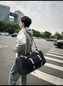 Uomo con borsa da viaggio sportiva nera su una strada, dettaglio di stile di vita urbano