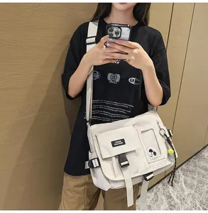 Minimalist cream nylon messenger bag for students, shown on model in workwear style