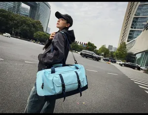 Vista lifestyle di una modella con una grande borsa da fitness blu bicolore in strada