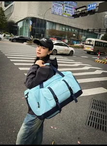Grande borsa da viaggio azzurra per sport e fitness indossata da una modella in città