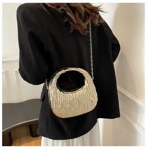 Model wearing a gold textured acrylic handbag with chain strap against a black blazer