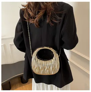 Back view of a chic gold textured acrylic handbag with chain strap worn on a black blazer