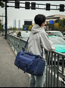 Grande borsa sportiva blu scuro indossata da un modello in un moderno contesto urbano