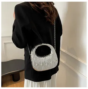 Macro view of a silver metallic textured handbag with chain strap on a black blazer