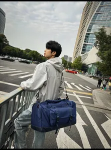 Grande borsa da viaggio blu navy indossata da un modello in un contesto urbano