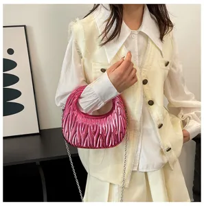Metallic pink pleated candy color handbag with silver chain strap shown with model.
