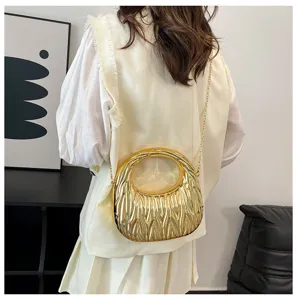 Detail view of gold metallic wavy pleated handbag worn over shoulder with chain