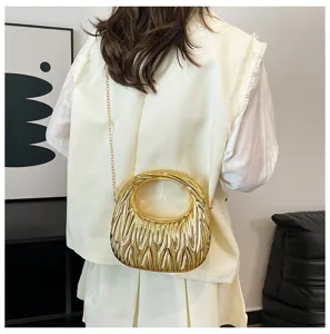 Detail view of gold metallic pleated handbag with chain strap worn by a model