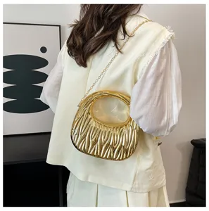 Detailed view of a golden metallic wave textured acrylic handbag on a model